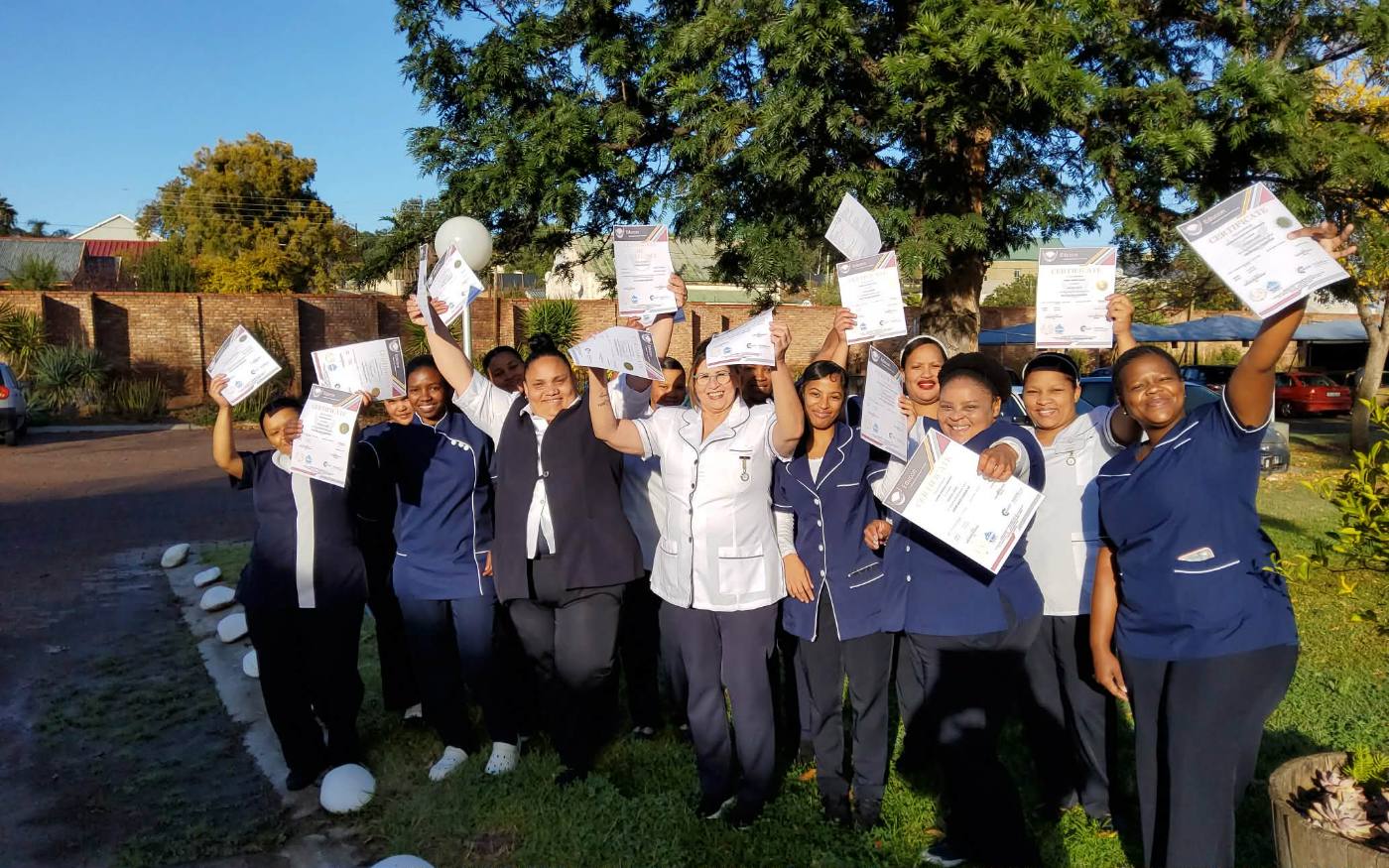 Graduating class holding certificates outdoors