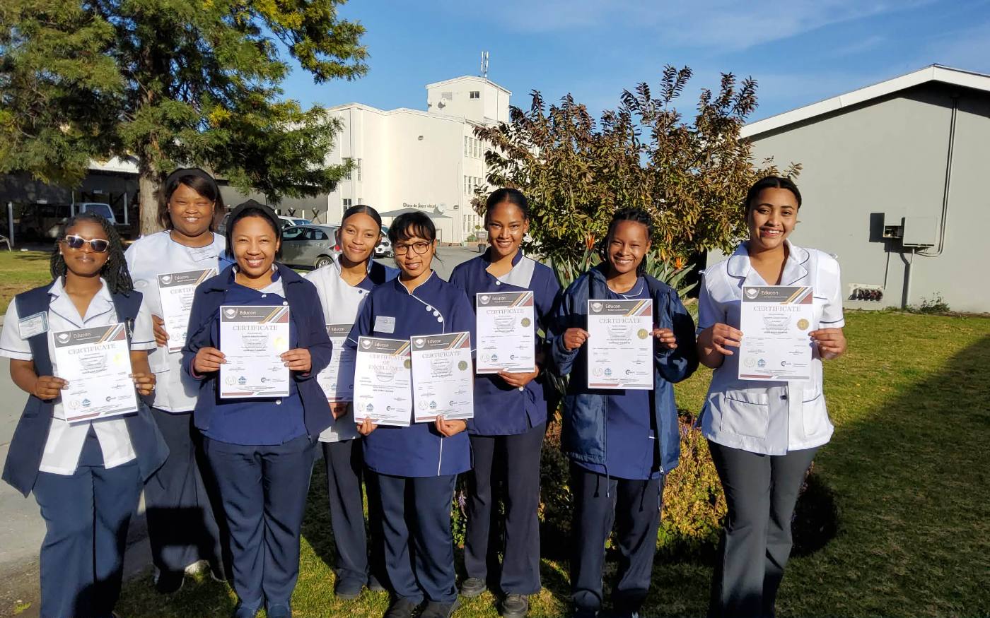 Graduating class holding certificates outdoors